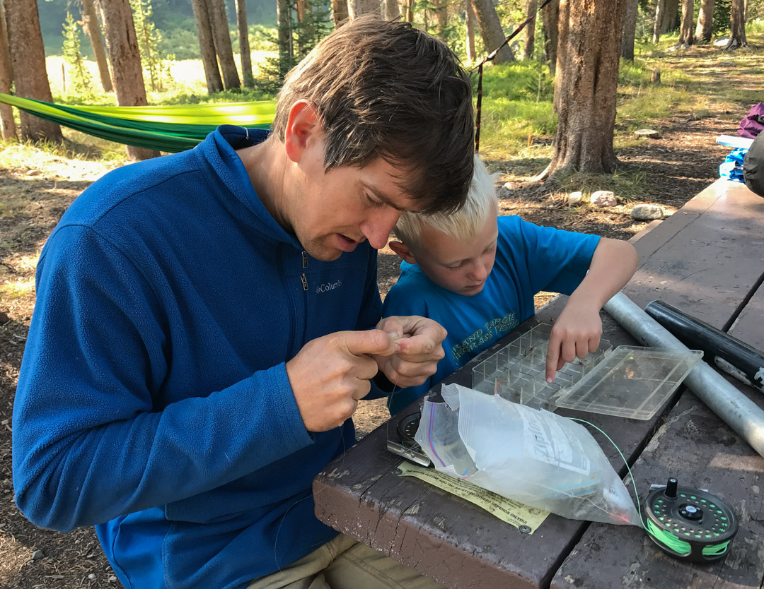 father and son choosing fly fishing flies from a box